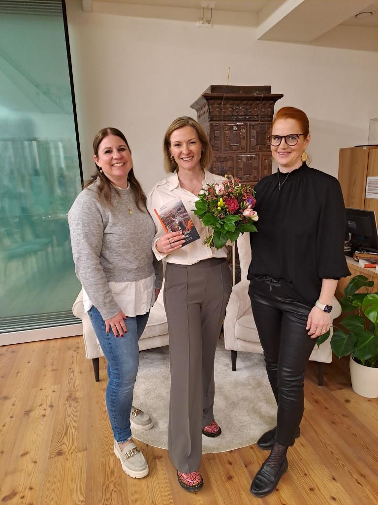 3 Personen: Autorin in der Mitte mit Blumenstrauß